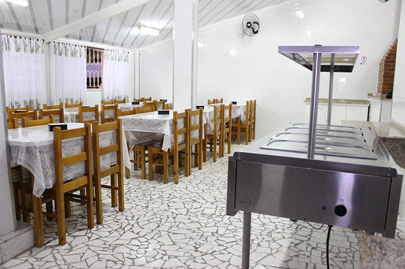 a dining room with tables and chairs and a tv at Pousada Santa Rosa in Aparecida