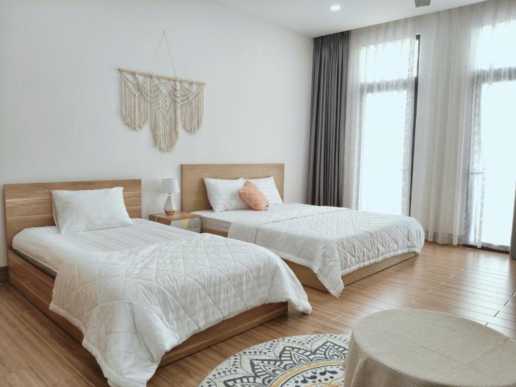 Gò CôngLà lá 1 Vinhome Grand Park的一间卧室，配有两张铺有白色床单的床