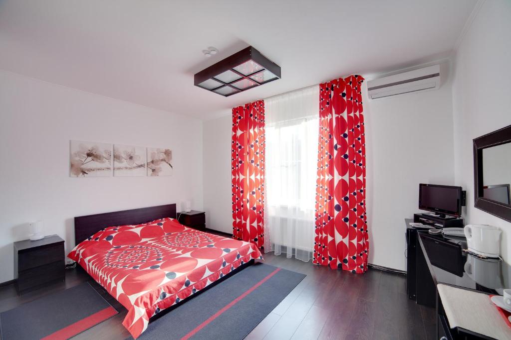 a bedroom with a red bed and red curtains at Hotel Odisseya in Ryazan