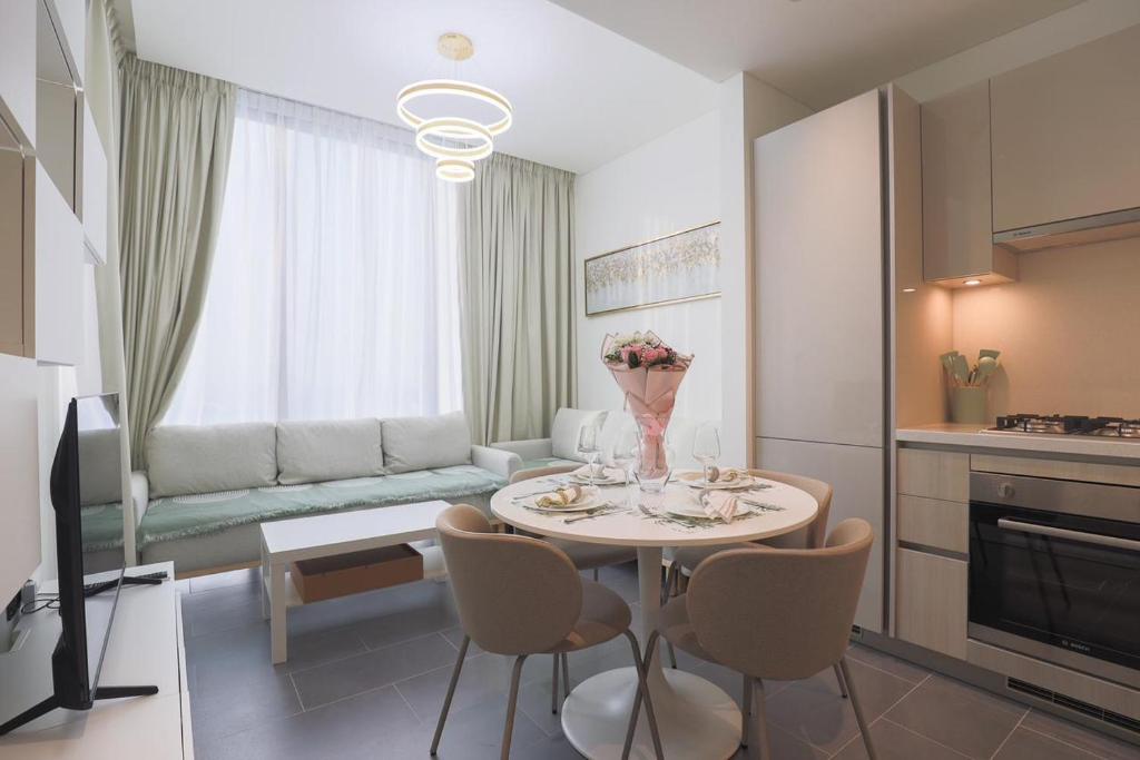 a kitchen and living room with a table and chairs at Gracious 1BR in The Crest, Sobha Hartland in Dubai