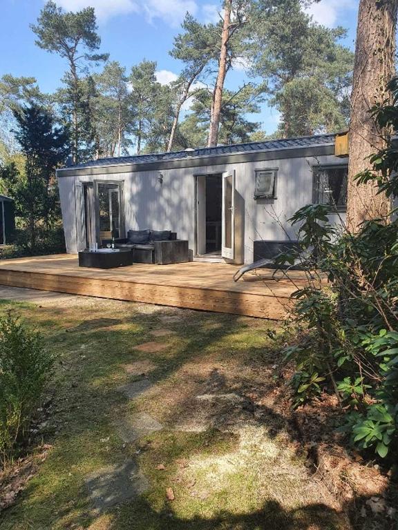 a small house with a porch and a wooden deck at Sfeervolle woodlodge op 5 sterren vakantiepark in Raalte