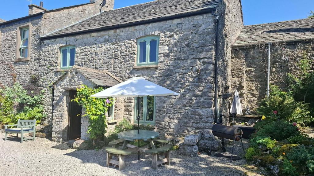 Ce cottage en pierre comprend un parasol et une table. dans l'établissement The Old Farmhouse, Yealand Redmayne, near Carnforth, à Beetham