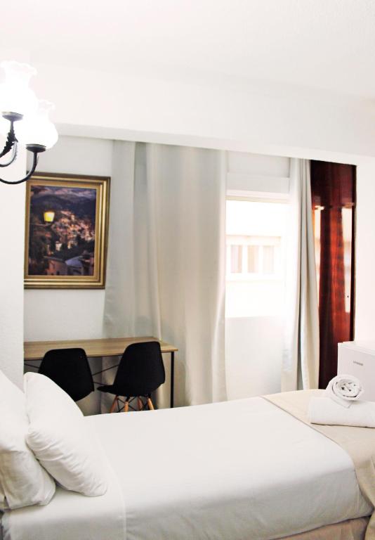 a hotel room with a bed and a desk with chairs at Pensión Eurosol in Granada