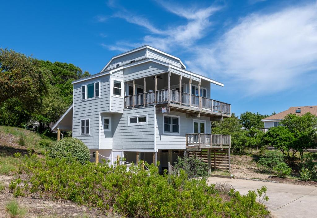a white house with a balcony on a hill at Serenity in Duck D4118 - 3 Min Walk to the Beach, Community Pool! in Duck