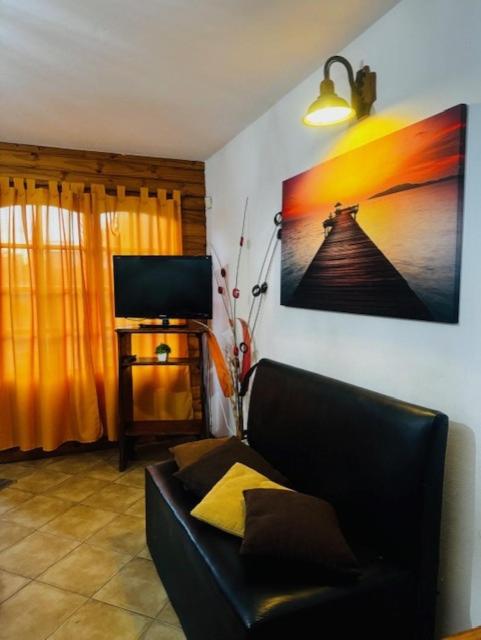 a living room with a couch and a tv at Cabañas Playa del Sol in San Clemente del Tuyú