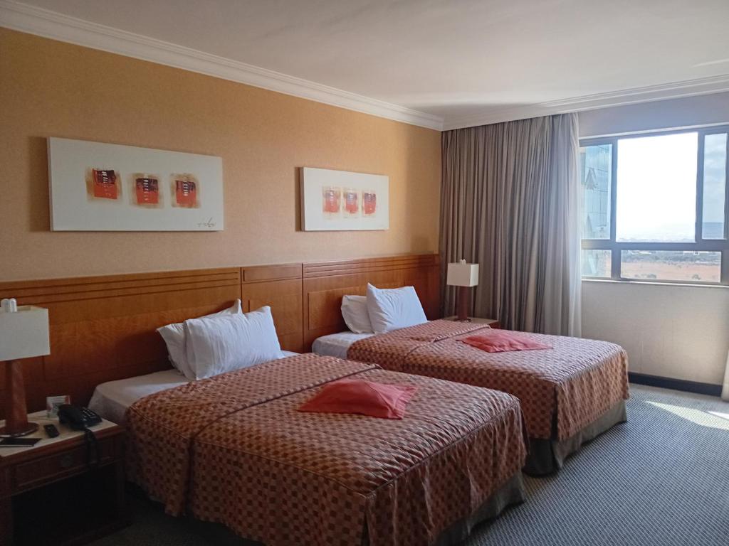Una habitación de hotel con dos camas y una ventana. en Condomínio Brasil 21 Torre D, en Brasilia