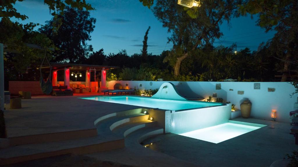 a swimming pool with lights in a backyard at night at Oliveyard Stone Built House- with pool non chlorin in Koskinou