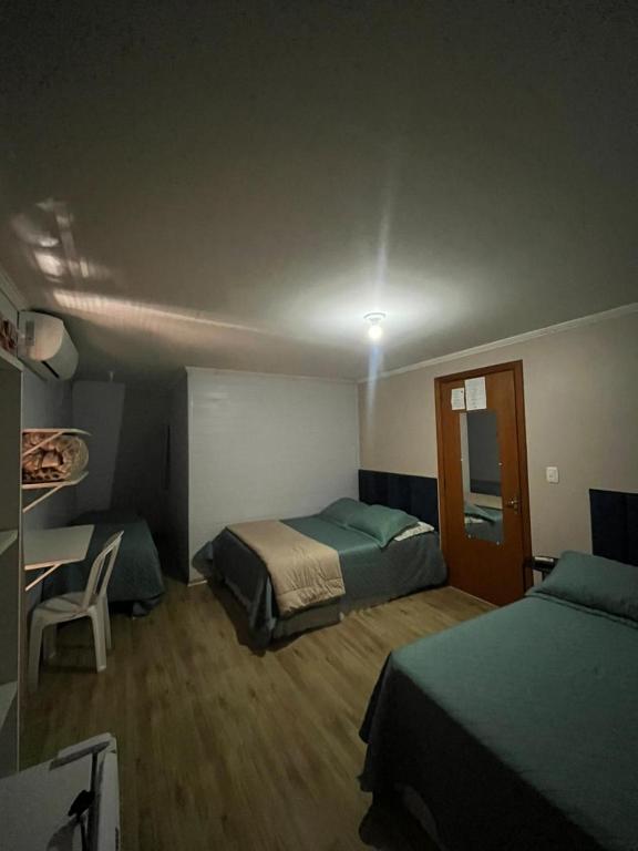 a bedroom with two beds and a table and a chair at Hotel Pousada do Mel in Gramado