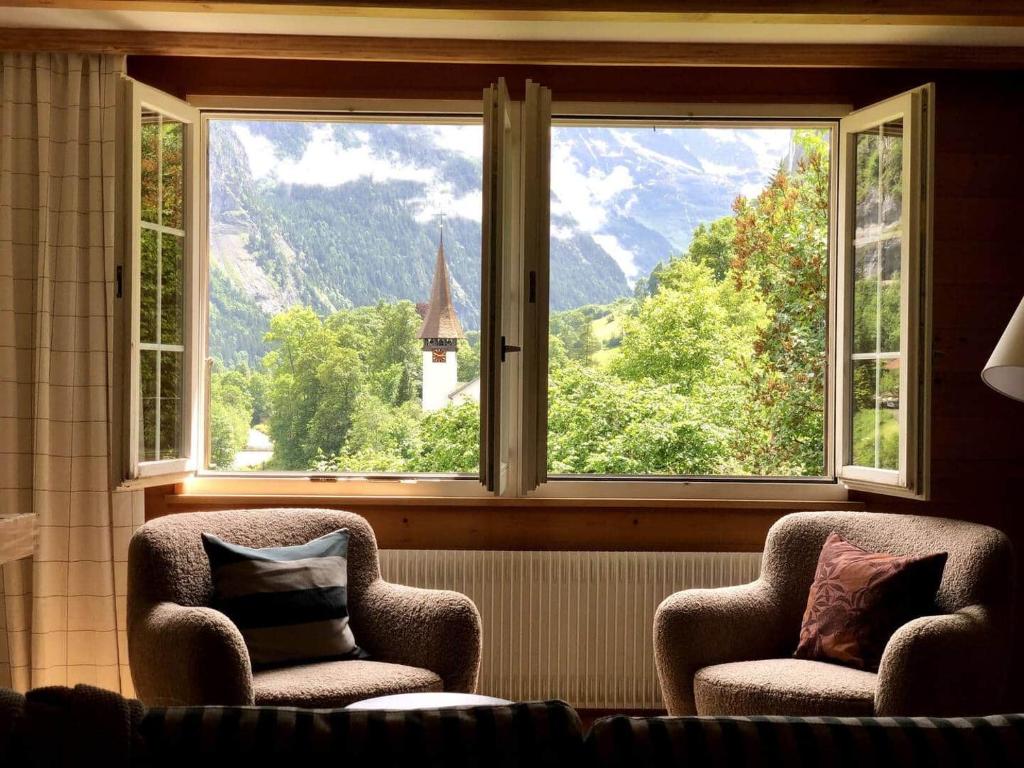 a room with two chairs and a window with a view at Waterfall Views-Stylish Design-Big Comfy Bed in Lauterbrunnen