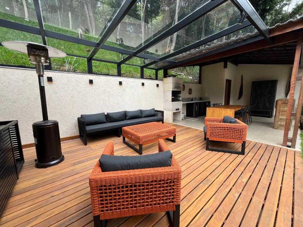 patio con sedie e mobili su una terrazza in legno di Casa 09 Floresta Boa Vista - Piscina Privativa, Jardim e Lazer Completo a Teresópolis