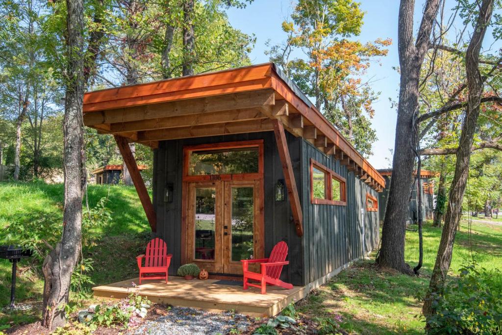 a tiny house in the woods with two red chairs at 1 Mile to Downtown West Jefferson Camping Cabin #1 in West Jefferson