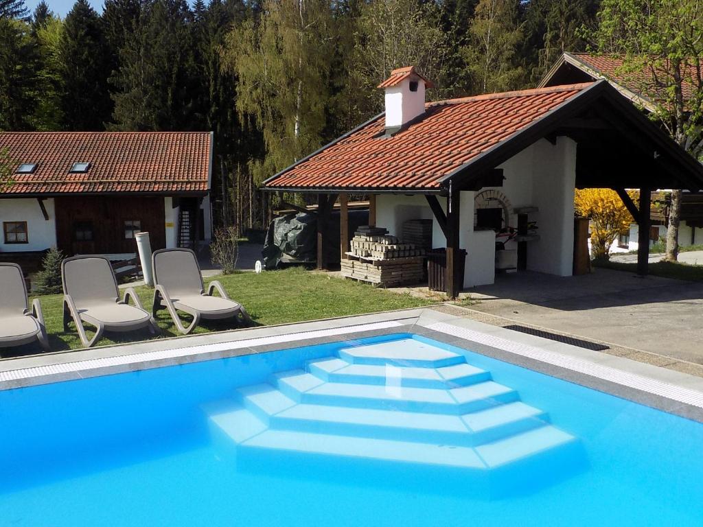 ein blauer Pool mit Stühlen und ein Haus in der Unterkunft Ferienwohnung für 4 Personen ca 60 m in Hauzenberg-Raßreuth, Bayern Bayerischer Wald in Hauzenberg