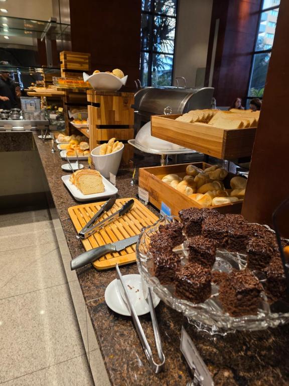 Una línea de buffet con diferentes tipos de pan y pasteles. en Quarto 5 estrelas no Comfort Suites!, en Brasilia