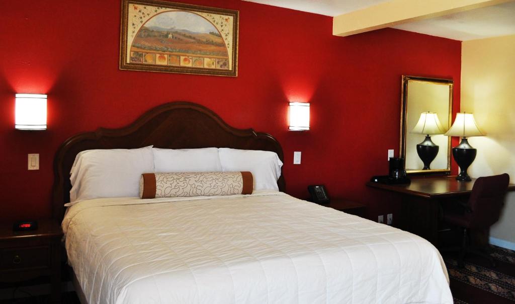 a bedroom with a white bed and a red wall at A Nights Inn in Ridgecrest
