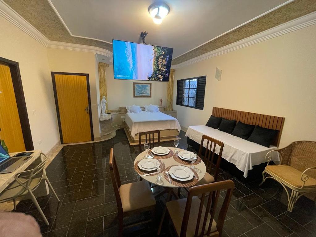 ein Wohnzimmer mit einem Bett und einem Tisch mit Stühlen in der Unterkunft Belíssima Casa Stella Maris -Casa de Carrara3 in Andradina