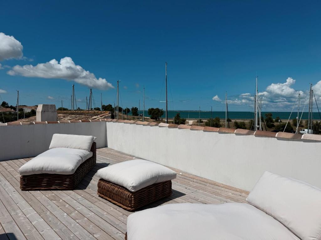 two chairs and ottomans on a balcony with the ocean at Maison - Vue mer - Clim et Piscine - 6 ch - 4 sdb - Sauna - St Martin de Ré in Saint-Martin-de-Ré