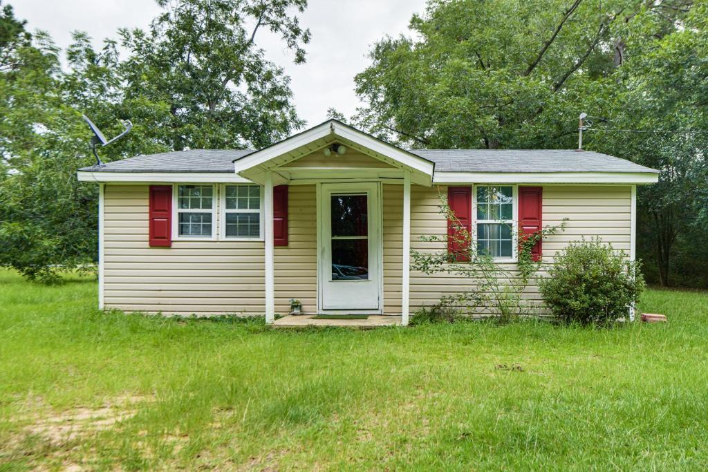 a small yellow house with a door in the grass at 6 Mi to Museum of Aviation Rural Kathleen Home in Bonaire