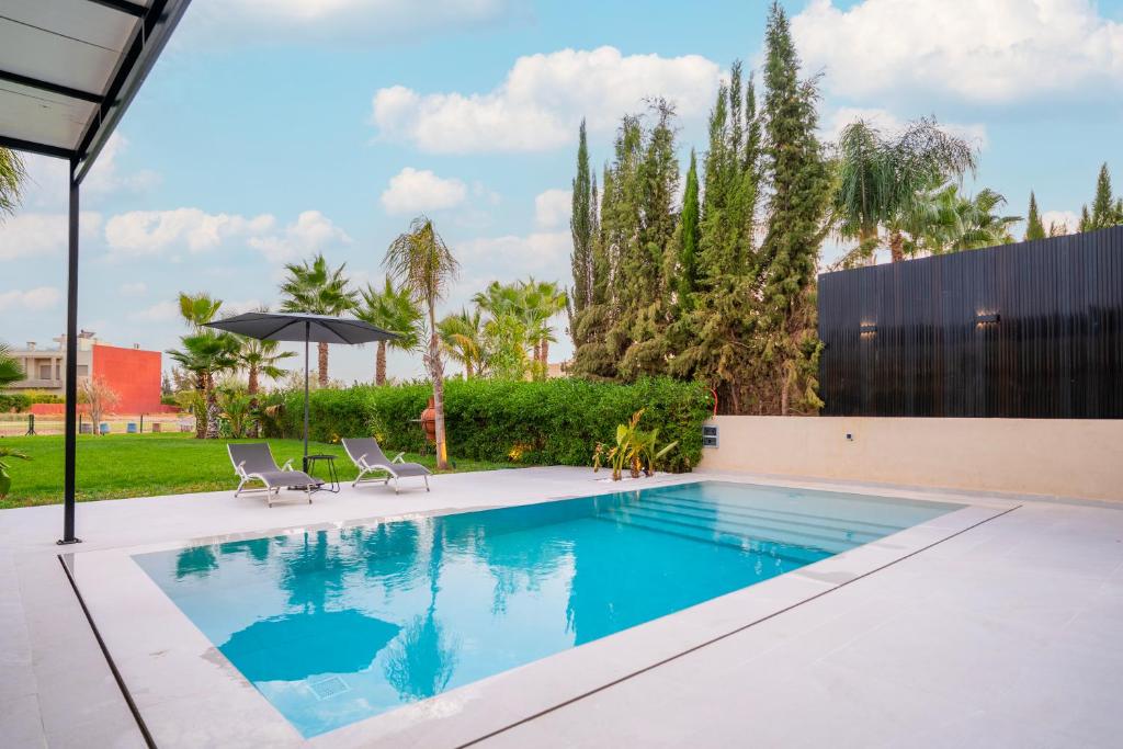 ein Swimmingpool mit zwei Stühlen und einem Sonnenschirm in der Unterkunft Villa Meraki in Marrakesch