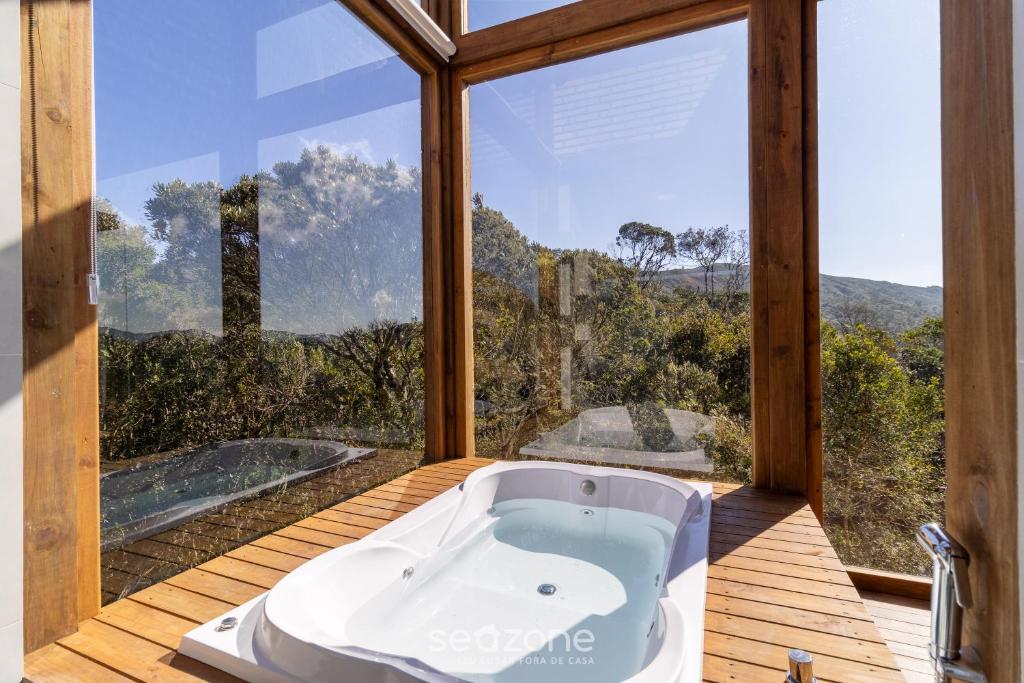 a bath tub in a room with a large window at Chalé Charmoso c/ Jacuzzi de Hidromassagem VST024 in São Paulo dos Pinhais