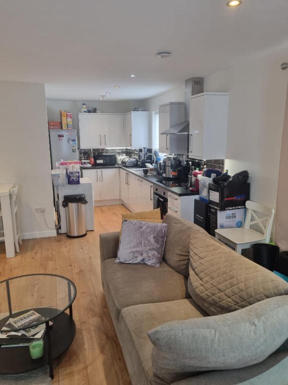 a living room with a couch and a kitchen at Fabulous two bedroom flat with concierge in Dagenham