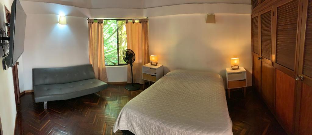 a bedroom with a bed and a chair and a window at Casa Campestre Poblado para 10H San Lucas 106 in Medellín