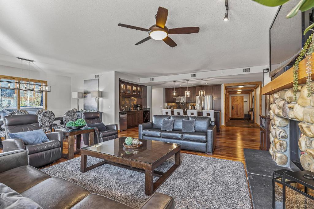 a living room with leather furniture and a ceiling fan at Spring Creek Condo by Canadian Rockies Vacation Rentals in Canmore