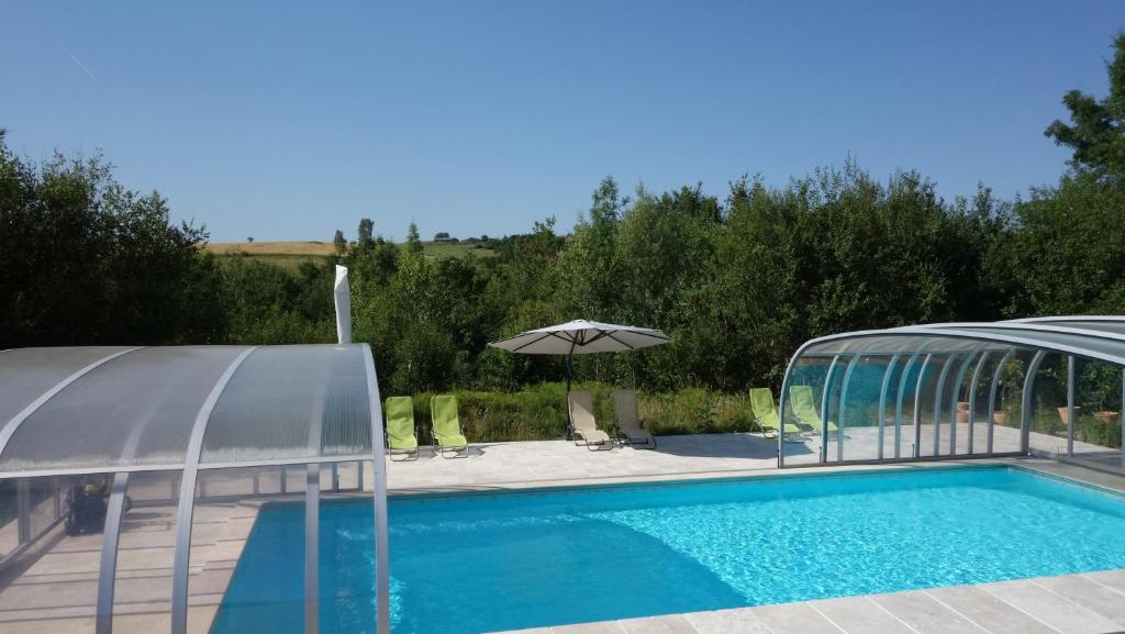 - une piscine avec un parasol à côté dans l'établissement St Victor Du Fau, à Pamiers
