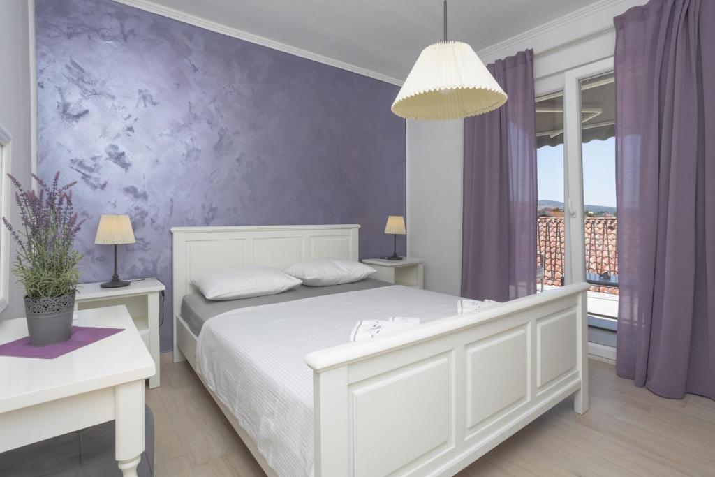 a bedroom with a white bed and purple walls at Dalma Residence apartman Lavandella in Zaboric