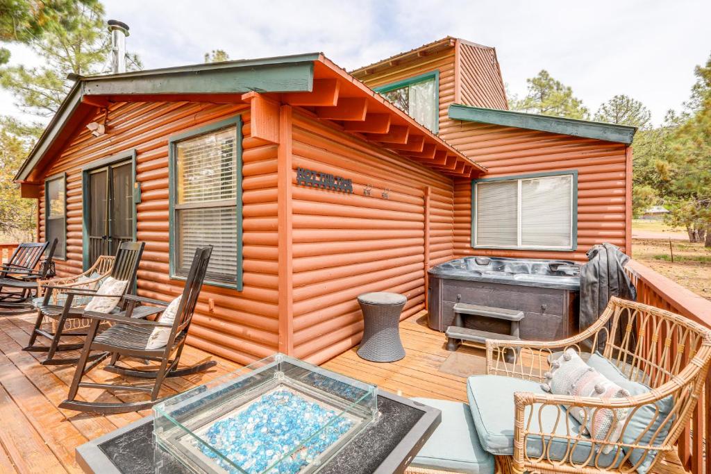 a cabin with a hot tub and chairs on a deck at Private Hot Tub and Fire Pit Pine Cabin Near Hiking in Pine