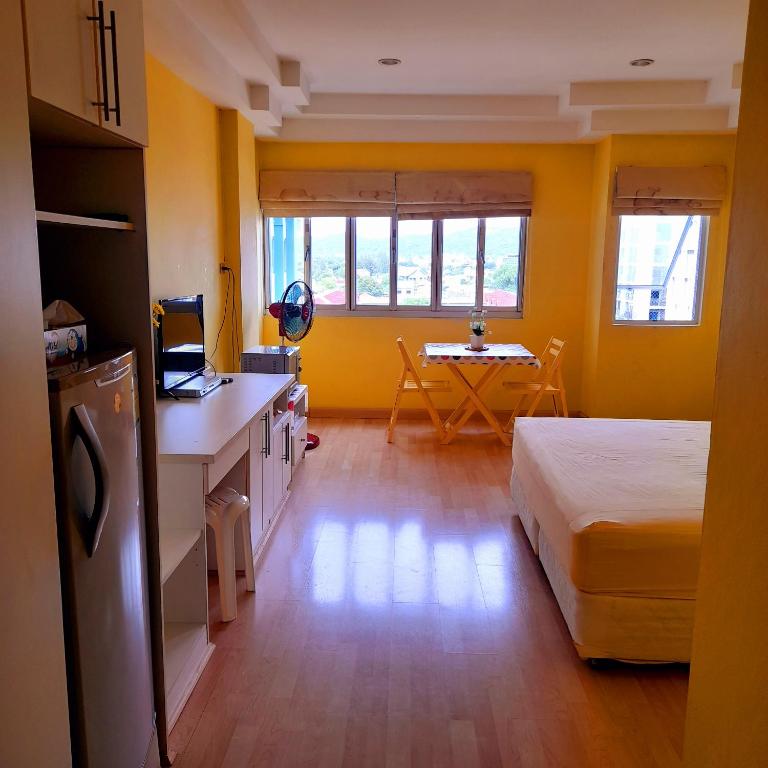 a yellow room with a bed and a table at Sport Villa Condo in Hua Hin
