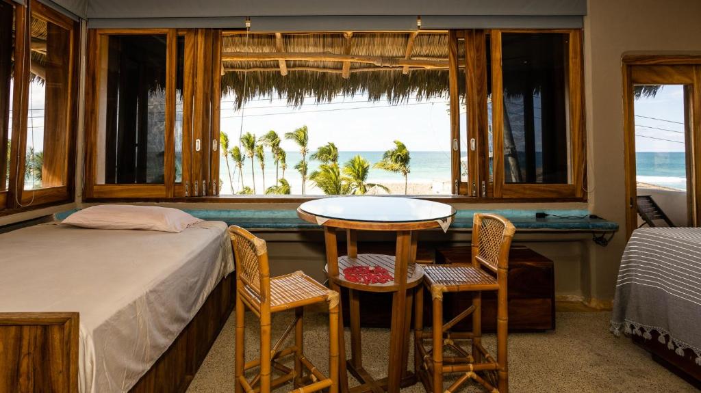 a bedroom with a bed and a table and chairs at Las Olas Litibu Bungalow By The Sea in Higuera Blanca