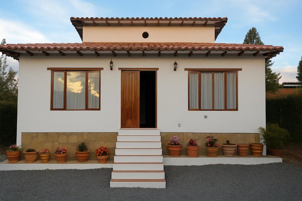 a small white house with potted plants at Cabaña familiar con 3 dormitorios y baños privados in Villa de Leyva