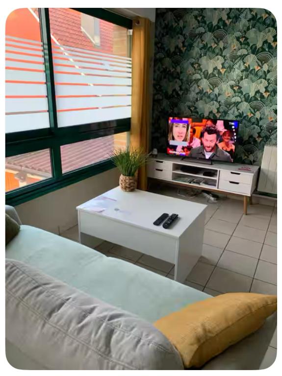 a living room with a bed and a tv and a table at Meublé bord de Mer in Gravelines