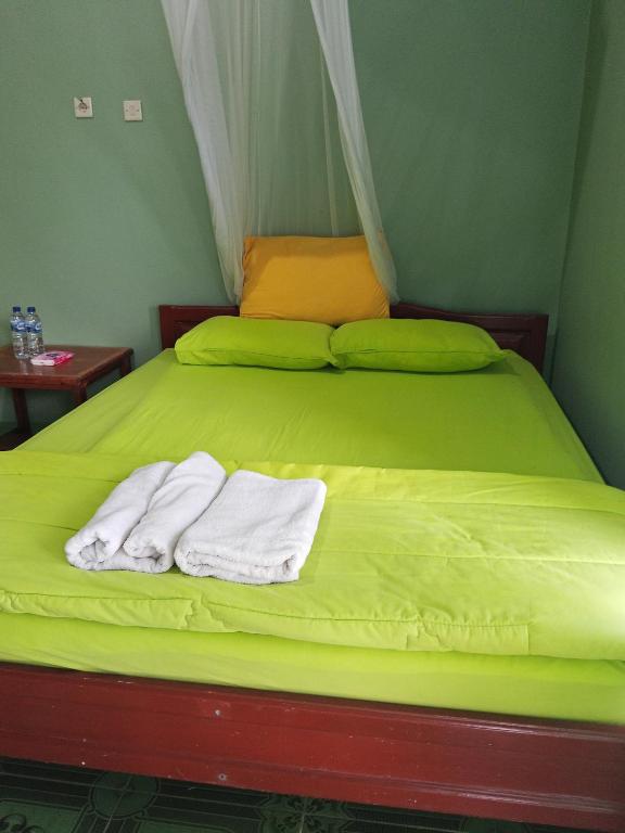 a green bed with two white towels on it at Kelimutu Lodge Moni in Kelimutu