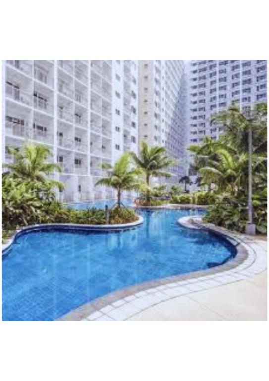 a large swimming pool in front of a large building at Stay Manila in Sampong