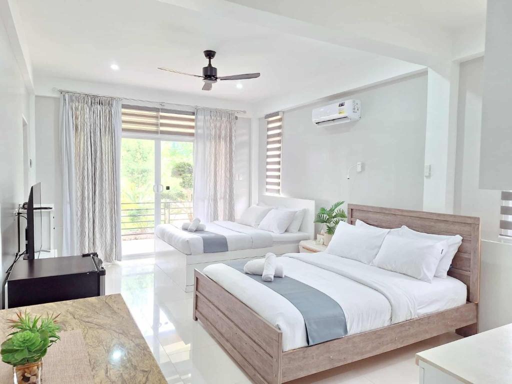 a bedroom with two beds and a television in it at INATO SUITES Rm 2 2 queen beds in Panglao Island