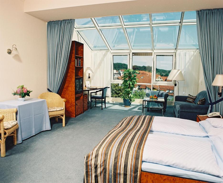 um quarto com uma cama e uma grande janela em Hotel Arkadia em Friedrichsdorf