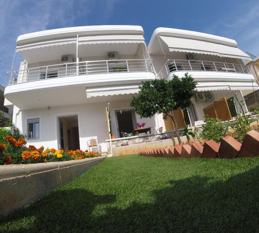 a white house with a lawn in front of it at Riviera Rooms in Himare