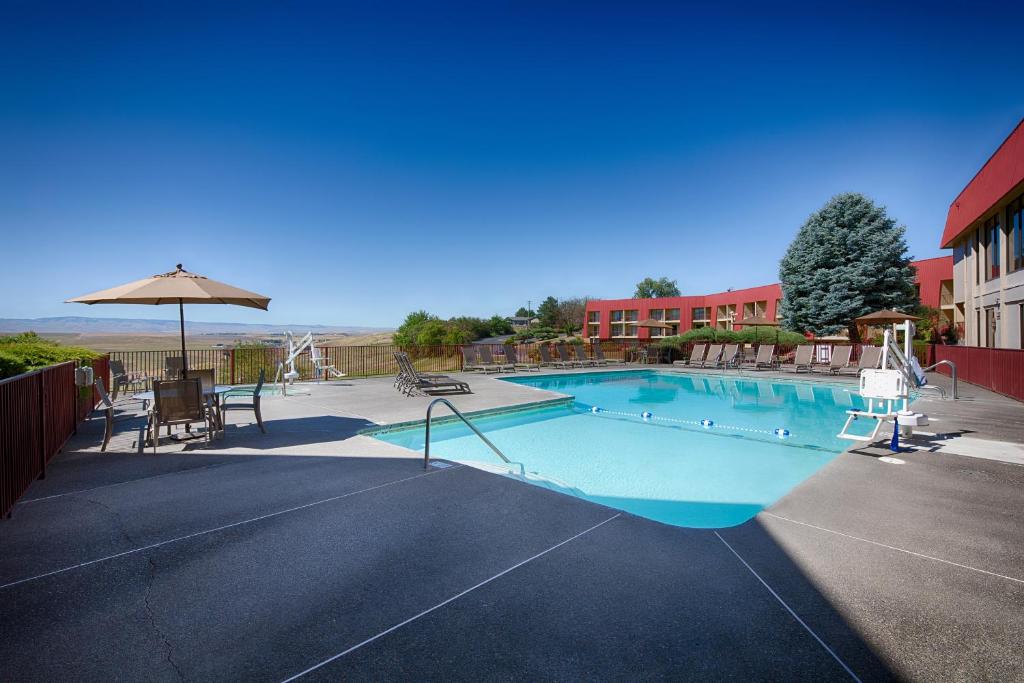 a large swimming pool with an umbrella and chairs at Red Lion Hotel Pendleton in Pendleton