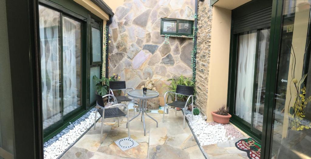 patio ze stołem i krzesłami oraz kamienną ścianą w obiekcie Pension Siete en el Camino w mieście Sarria