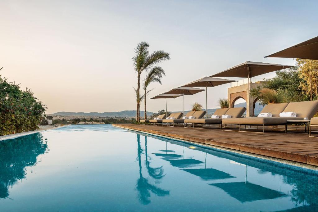 a swimming pool with lounge chairs and palm trees at Hotel Sahrai in Fès