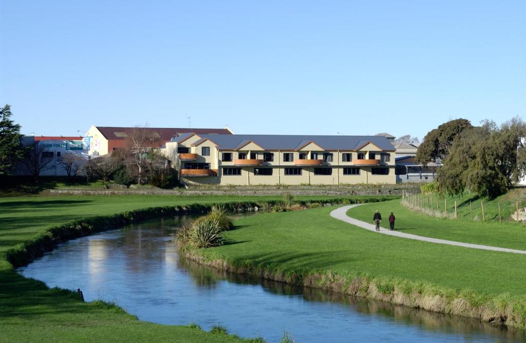 duas pessoas caminhando em um caminho ao lado de um rio em Waterfront motel em Blenheim