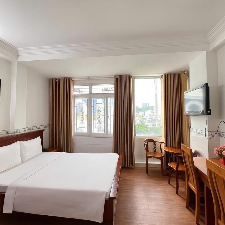a hotel room with a white bed and a table at TK Diamond Hotel - Saigon Center in Ho Chi Minh City