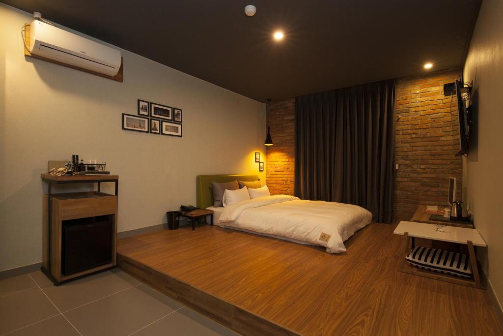 a bedroom with a bed and a brick wall at Hotel Gray in Changwon