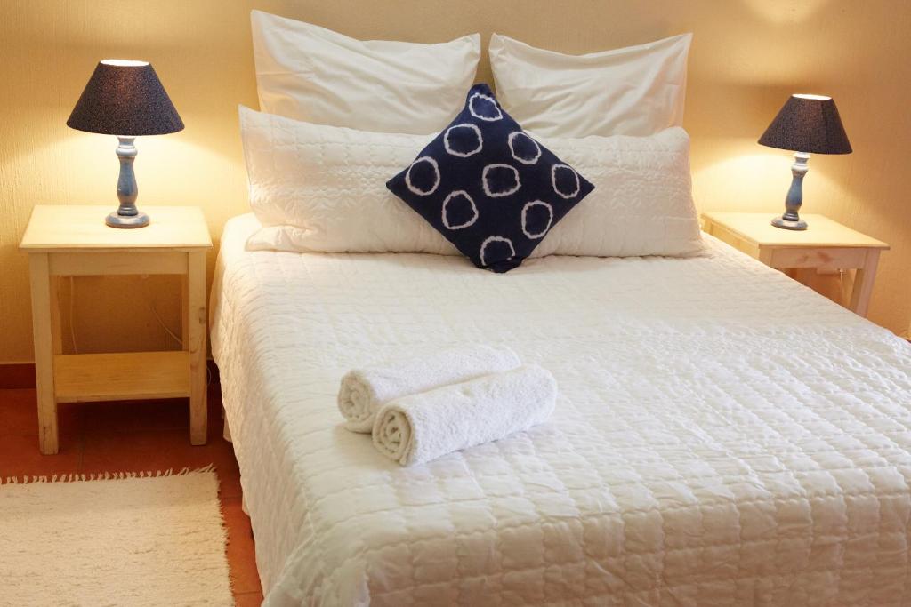 una camera da letto con un letto bianco e asciugamani di The Fever Tree Guest House a Hluhluwe