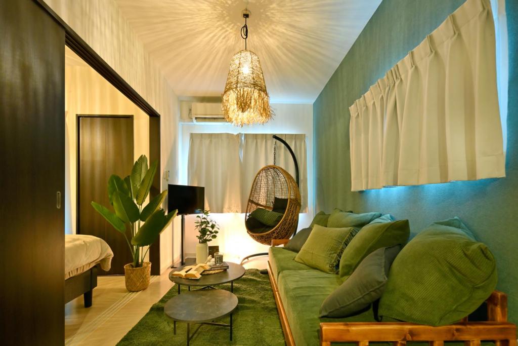 a living room with a green couch and a chandelier at Otter Stay - Masaki in Nagoya