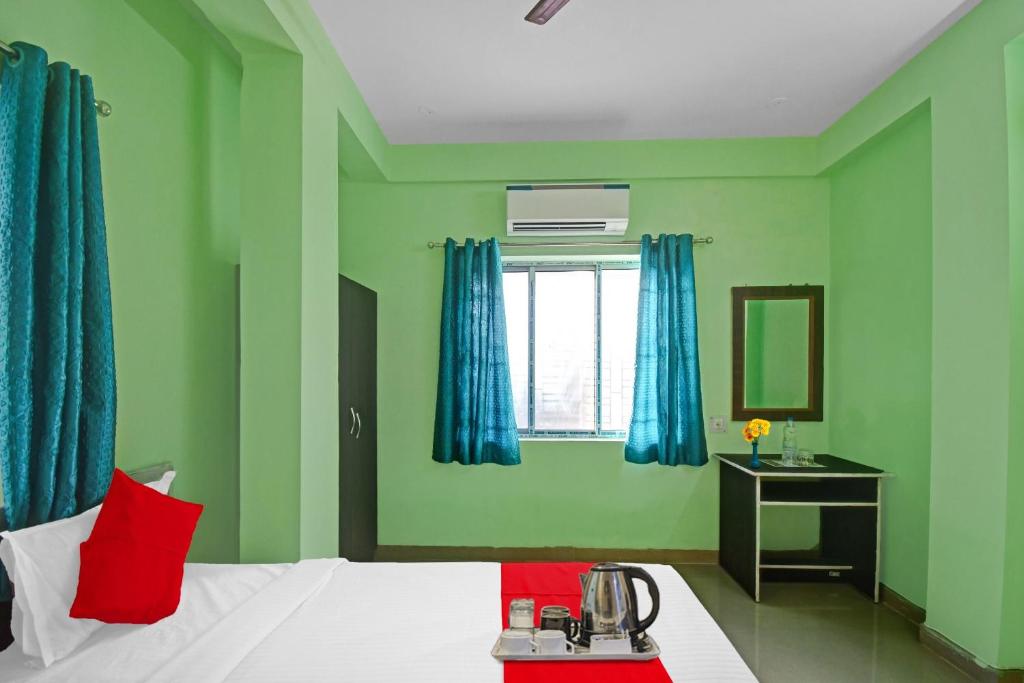 1 dormitorio con paredes verdes y 1 cama con cortinas azules en Hotel O Hotel Acronis, en Calcuta