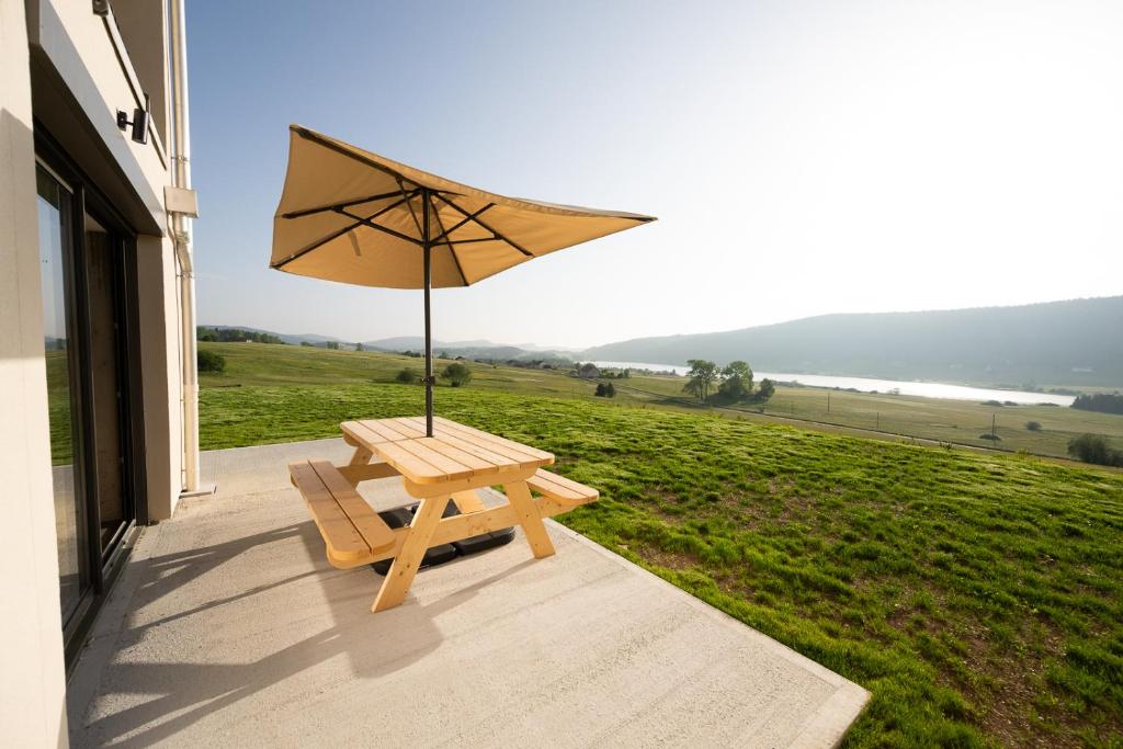 a wooden bench with an umbrella on a porch at Le 214, Entre Lacs et Montagnes in Les Rousses