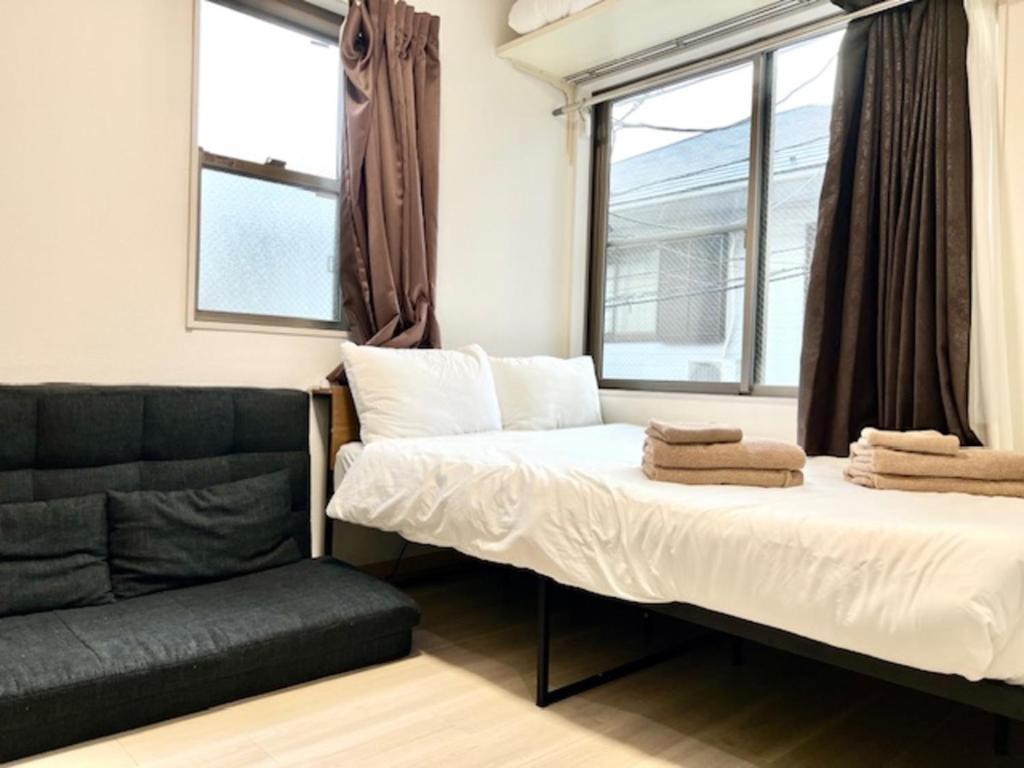 a bed and a couch in a room with windows at グレイシャス東新宿 東新宿駅徒歩3分 新大久保駅徒歩7分 新宿駅徒歩15分 歌舞伎町すぐ近く 美味しい韓国料理屋多数あります in Tokyo