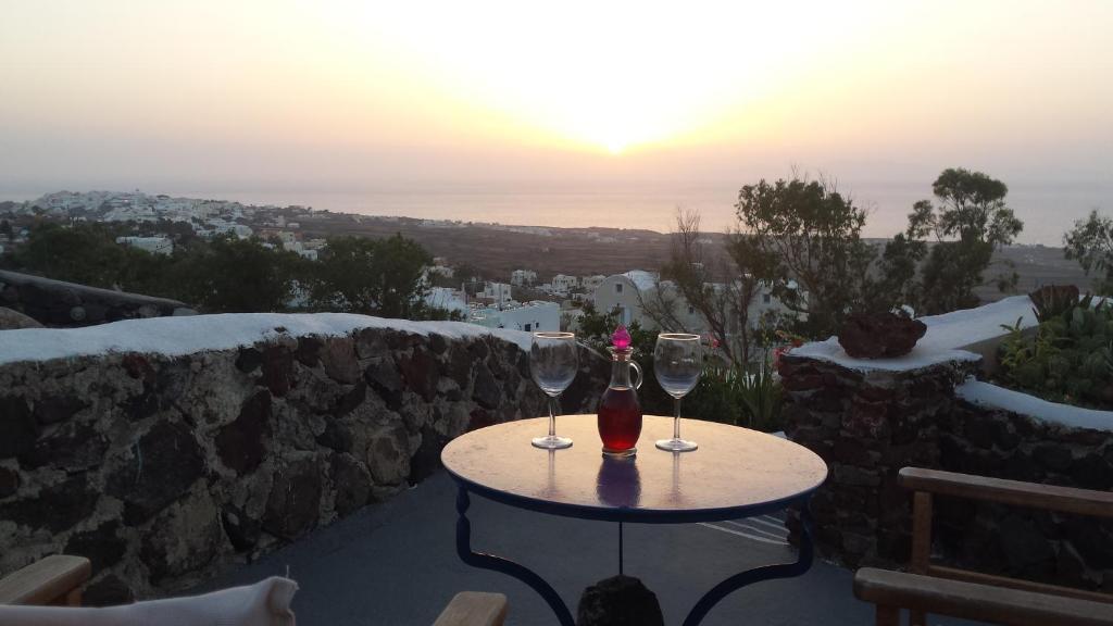 two glasses of wine sitting on a table with the sunset at Alonistra Oia Houses in Oia